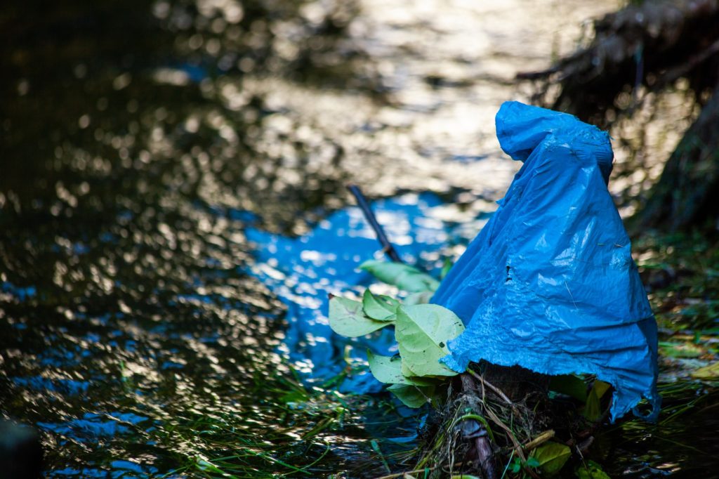 Plastik am Flussrand. Überreste eines blauen Plastiksacks findet den Weg in den Wasserkreislauf.